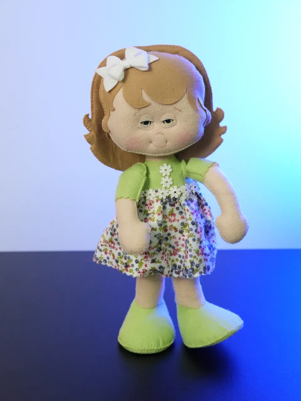 A Jhully: boneca de feltro de cabelo caramelo com laço branco, blusa verde e saia florida